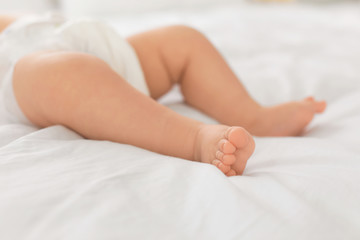 Obraz na płótnie Canvas Cute little baby lying on bed, closeup of legs