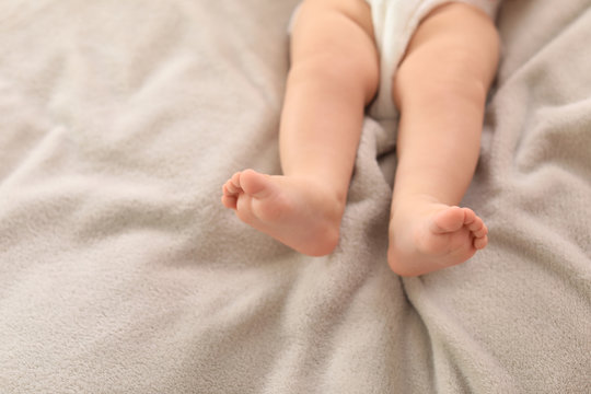 Cute little baby lying on bed, closeup of legs. Space for text