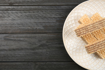 Plate with delicious crispy wafers on wooden table, top view. Space for text
