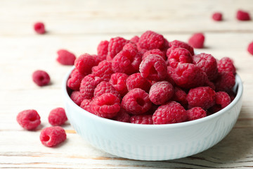 Bowl of delicious fresh ripe raspberries on white wooden table, closeup view