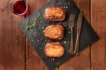 Sirloin beef steaks with salt, rosemary, and red wine, shot from above on a black slate plate