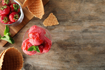 Flat lay composition with delicious strawberry ice cream on wooden table, space for text
