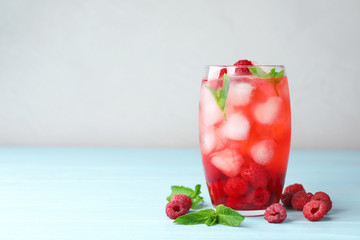 Glass of raspberry refreshing drink on blue wooden table, space for text