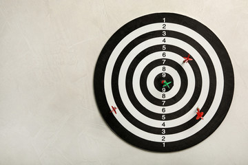 Dart board with color arrows on light stone background, top view. Space for text