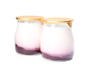 Glass jars of tasty fruit yogurt on white background
