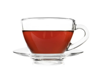 Glass cup of tea and saucer on white background