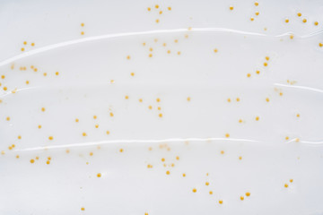 Smears and texture of white face cream with yellow peas on a white background