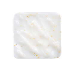 Smears and texture of white face cream with yellow peas on a white background