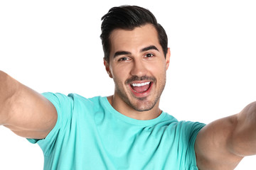 Fototapeta premium Happy young man taking selfie on white background