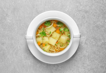 Dish of fresh homemade vegetable soup on light grey background, top view