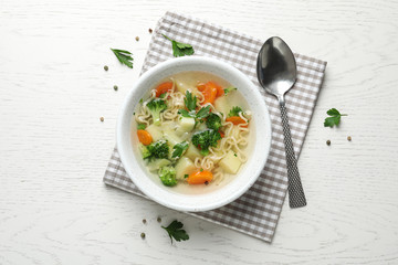 Bowl of fresh homemade vegetable soup served on white wooden table, flat lay