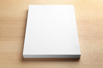 Stack of blank paper sheets for brochure on wooden background. Mock up