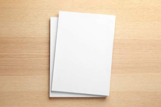 Stack of blank paper sheets for brochure on wooden background, top view. Mock up
