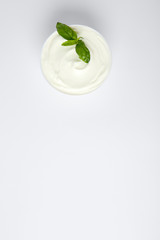 Bowl of fresh sour cream with basil on white background, top view