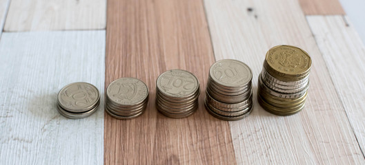 Savings, increasing columns of coins isolated on white background and wooden table