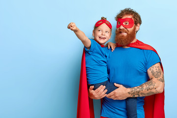 Happy daughter and father have supernatural power, little girl makes flying gesture, wear superman...