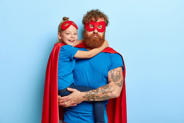 Serious tired dad entertains child on party, pretend being superheroes, have extraordinary power,...