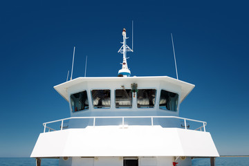front view of  the navigation cabine on a passenger ship on blue sky background © ThomasLENNE