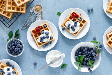 Traditional belgian waffles with cream cheese and fresh blueberry on blue background, top view