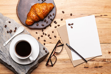 Coffee with coffee beanand and Croissant note  pad  on wooden table