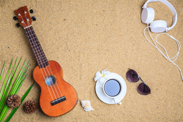 Ukulele with note paper,Coffee,Headphones and seashell on the beach