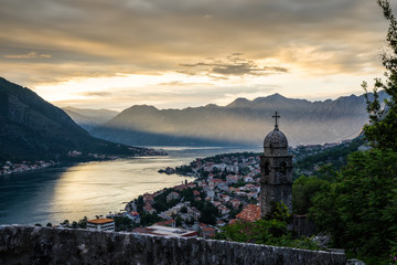 Montenegro, Historic church building and roofs of kotor bay old town from above in majestic sunset twilight atmosphere from above orange sky