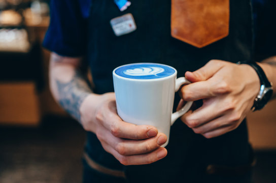 Closeup image of male hands holding cup of blue matcha latte