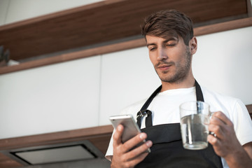 attractive young man reading a recipe on his smartphone