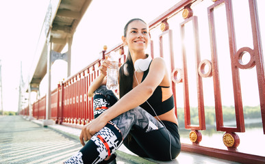 Woman is drinks water while resting after morning run