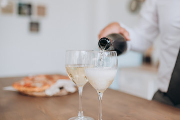 man pouring champagne into 2 glasses