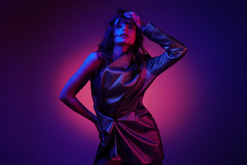 Fashion model in stylish clothing on color neon lights in studio