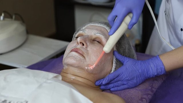 girl at the beautician. Cleaning the face. Darsonvalization.