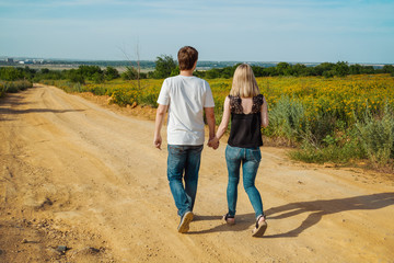 young couple walking on pathway through grass field.