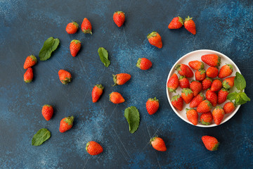 Fresh red strawberries on a blue concrete background.