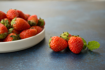 Fresh red strawberries on a blue concrete background.