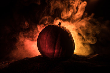 Halloween theme with pumpkin against smoky dark background. Empty space for text