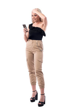 Relieved young woman with hand on forehead using smart phone. Full body isolated on white background. 