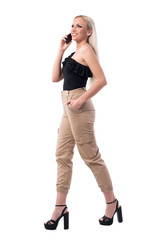 Happy excited woman walking and talking on the phone looking up. Side view. Full body isolated on white background. 