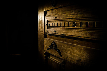 Close up view of old antique wooden door inside dark room. Selective focus