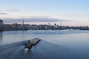 Naklejka premium The barge floating in the Dnieper river. Kyiv city landscape in the background. 17.11.2018