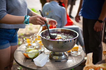 The girl pours a punch into a glass. Party in the open air. Light alcoholic drinks for friends. Rest in the city with drinks.