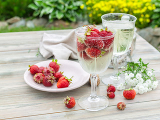 Sparkling wine and strawberries. Summer composition on a wooden table.
