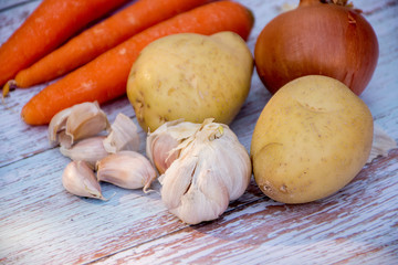 Potatoes, garlic and brown onions on a wooden table background. Cooking ingredients. Harvest