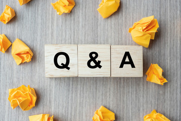  Q&A word with wooden cube block and yellow crumbled paper on table background. FAQ( frequency...