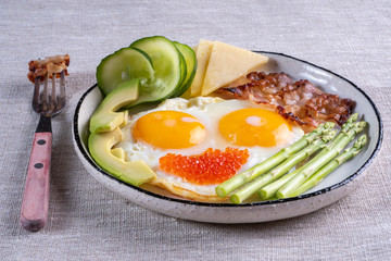 Close up view of the ketogenic diet breakfast on the white plate with a fork on linen fabric.