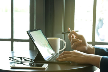businessman point the stylus pen to tablet for analysis graph visualization at coffee shop