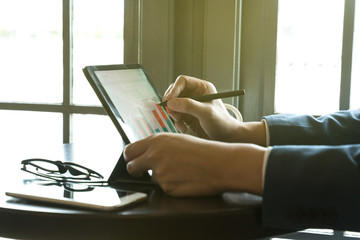 businessman using  drawing comment in tablet for analysis graph visualization at coffee shop