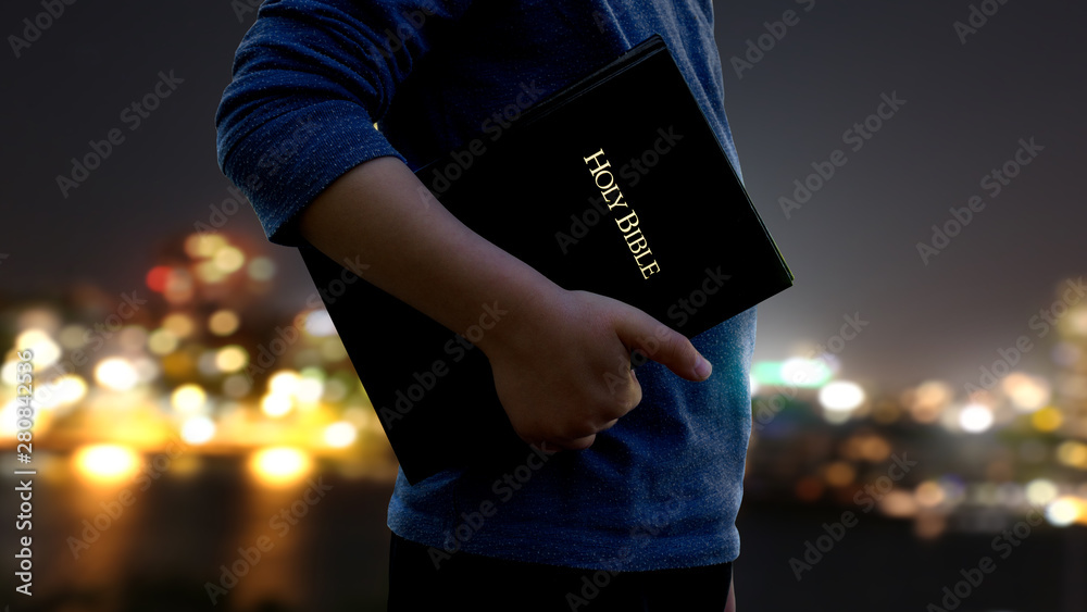 Wall mural man carrying a Bible at his side