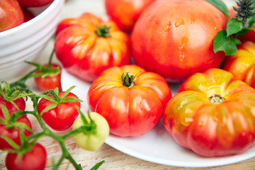 Mix of tomatoes background. Beautiful juicy organic red tomatoes on white wooden table background. Clean eating concept. Copy space, flat lay..