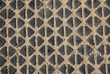 Old gray and black concrete embossed texture on the road, background with triangles and rhombuses for design.
